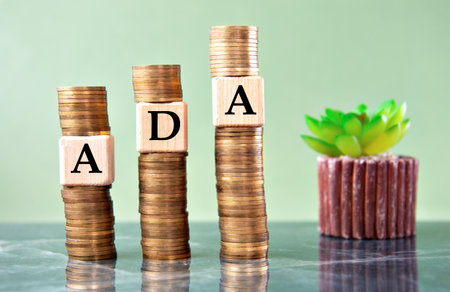 ADA - acronym on wooden cubes on stacks of coins. Business concept