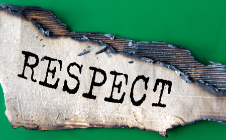 RESPECT - word on green paper against the background of a sheet of paper damaged by fire