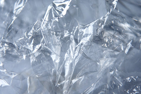Crinkled cellophane texture with glossy surfaces in shades of grey and translucent highlights...