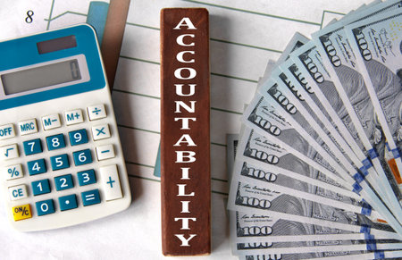 ACCOUNTABILITY - word on brown wooden blocks on the background of a graph and banknotes