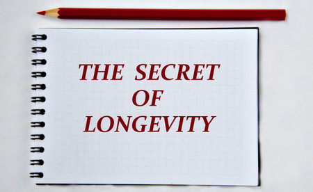 THE SECRET OF LONGEVITY - word in notebook on white background with pencils.の写真素材
