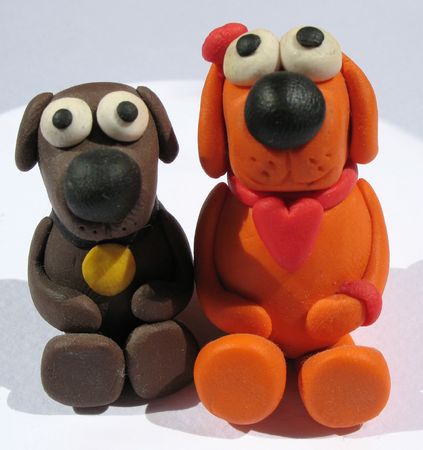 A plasticine toys. Handmade. The little funny dogs on the white background. A plasticine toys. Handmade. The little funny dogs on the white background.