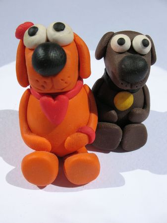A plasticine toys. Handmade. The little funny dogs on the white background. A plasticine toys. Handmade. The little funny dogs on the white background.