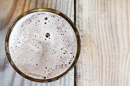 Glass of beer on wooden table, top view