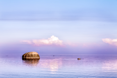 A large rock in the lake against a background of beautiful clouds.の写真素材