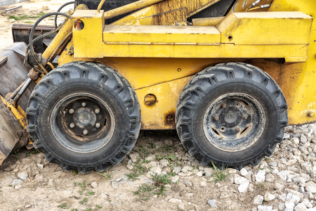 Close-up of a yellow mini excavator wheel on a construction site. In summer.の写真素材