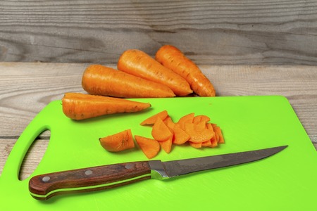 Carrots with a kitchen knife lying on the boardの写真素材