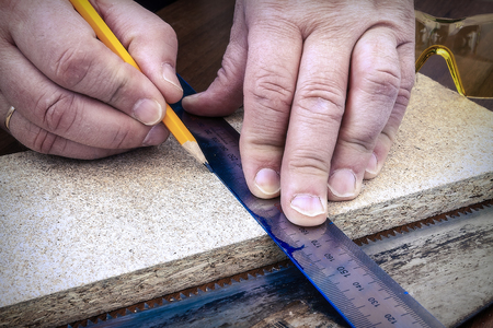 A person marks a wooden board with a pencil and ruler.の写真素材