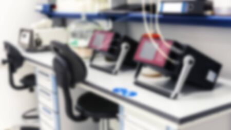 The background is blurry. Devices are on the tables in the test laboratory