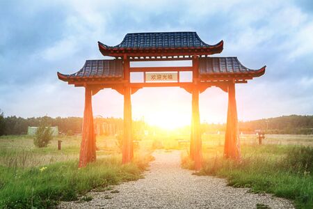The gates of a Chinese monastery against the backdrop of the rising sun.の写真素材
