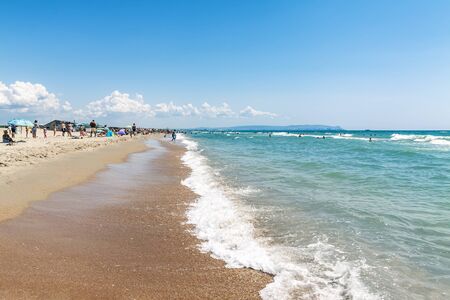 Anapa, Russia, 24.07.2019 On the sandy beach is a car and vacationers on a background of blue sky.のeditorial素材