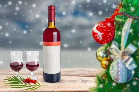 New Year theme. Wine bottle with glasses of wine on the background of falling snow.の写真素材