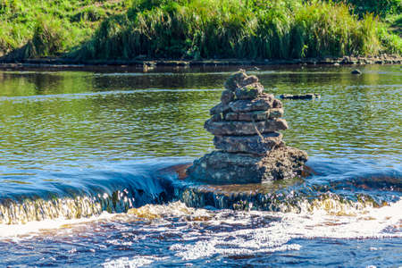 Tourists built a pyramid of small stones in the middle of the river.の写真素材
