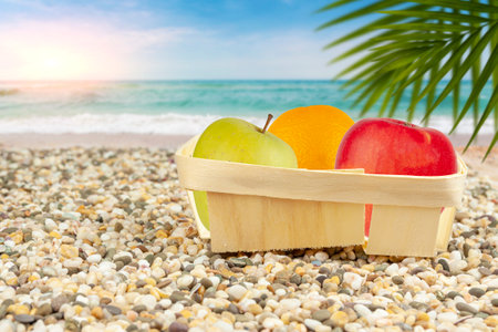Packaged apples and oranges lie on the beach by the sea.の写真素材