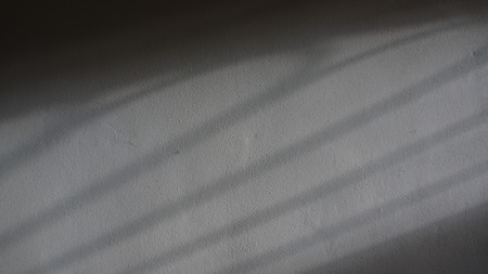 Shadows projected on a Plaster Grey Concrete Wallの写真素材