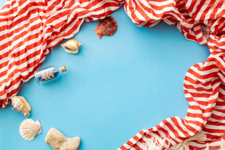 summer background: a boat in a bottle and seashells on a blue background