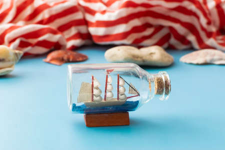 summer background: a boat in a bottle and seashells on a blue backgroundの写真素材