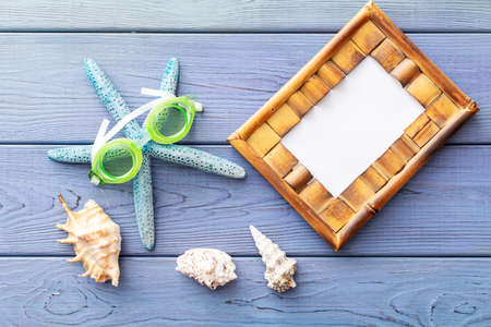 summer background: photo frame, starfish, seashells on a blue wooden backgroundの写真素材