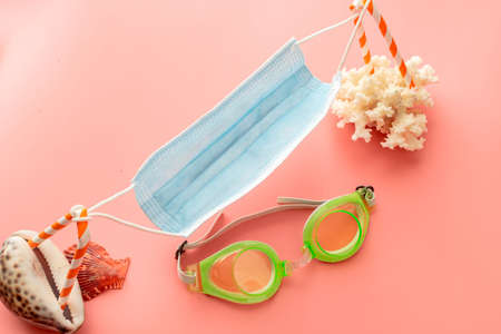 background image with summer vacation concept during quarantine: coconut with medical mask and sunglasses on pink backgroundの写真素材