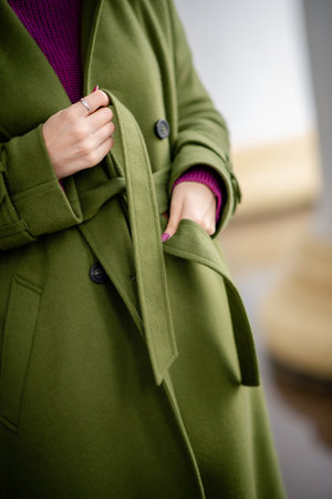 the girl's hands are tying the belt of the coatの写真素材