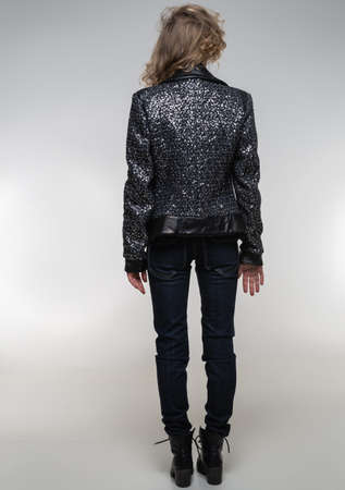girl in a black jacket with sequins and jeans, casual wear on a white backgroundの写真素材