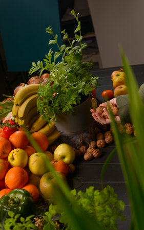 A table full of fruits and vegetables, including bananas, apples, oranges, and nuts. A person is...