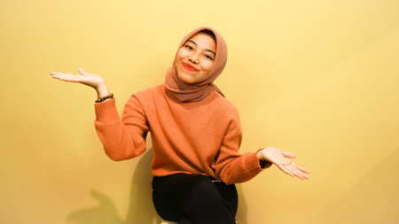 Attractive beautiful Asian woman sitting on chair with happy feeling of happiness isolated on orange background.の写真素材