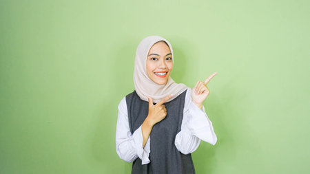 happy young asian woman in casual shirt. Charming female lady open hands palm up holding something on isolated green background.の写真素材