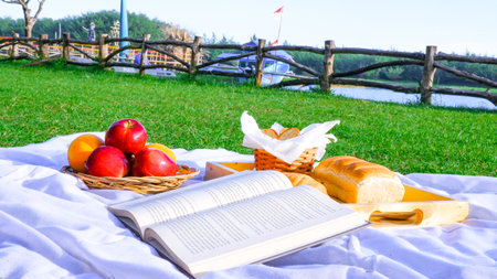 Basket of fresh fruits, bread, croissants and a book on the grass. Picnic conceptの写真素材