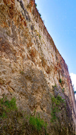 Rocky cliff with green grass and blue sky, natural background.