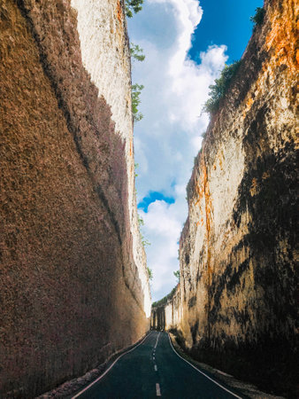 a road flanked by cliffs to the beach, Bali, indonesiaの写真素材