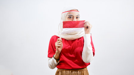 Portrait of Happy young Asian woman celebrate Indonesian independence day on 17 August by holding the Indonesian flag isolated over white backgroundの写真素材