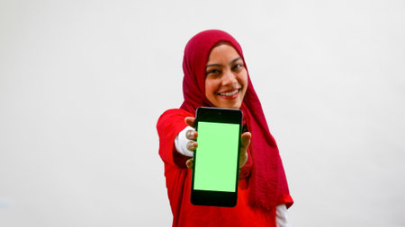 Excited young Asian women celebrate Indonesian independence day on 17 August while holding smartphone with blank screen isolated over white backgroundの写真素材