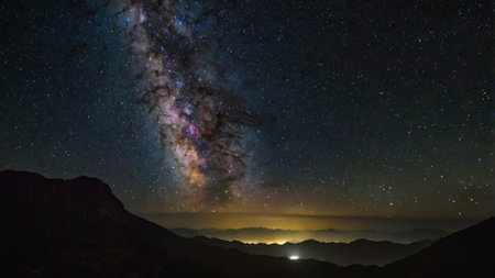 Milky Way over the mountains at night with stars and clouds.の写真素材