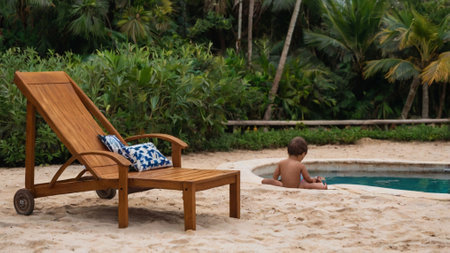Boy lying on chaise longue near swimming pool in tropical resortの写真素材