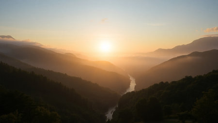Sunset in the mountains with a river in the foreground and fog in the background