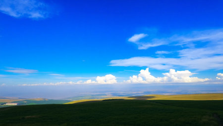 Beautiful landscape of green grassland and blue sky with white cloudsの写真素材
