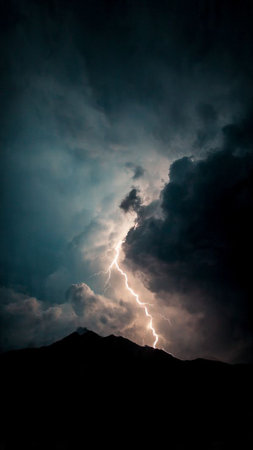 Lightning in the sky with clouds and mountains on the background.の写真素材