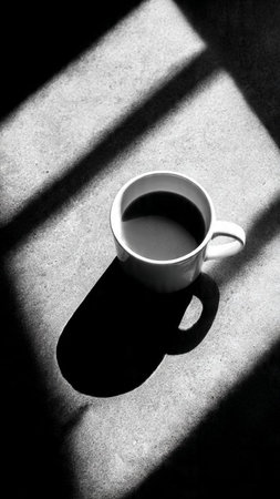 Cup of coffee with shadow on the floor. Black and white.の写真素材