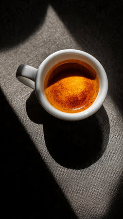 Cup of coffee on a dark background with shadow from the windowの写真素材