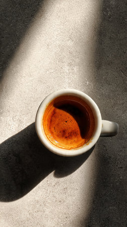 Cup of coffee on the table with shadow, top view.の写真素材
