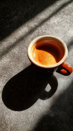 Cup of coffee with shadow on the table. Selective focus.の写真素材