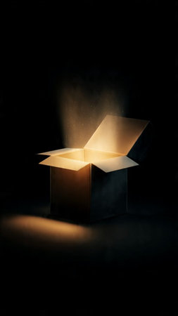 Open gift box with light coming out of it on a black backgroundの写真素材