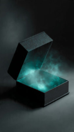 Black gift box with blue light inside on a black background with smokeの写真素材
