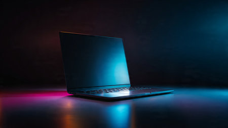 Laptop with a blue screen on a dark background with a beam of light.の写真素材