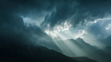 Dramatic sky with sunbeams and dark clouds over mountainsの写真素材