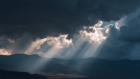 Dramatic sky with sunbeams and clouds over the mountainsの写真素材