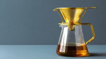 Coffee pouring in a glass decanter on a gray background