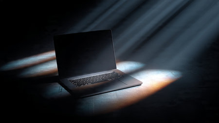 Laptop in dark room with beam of light. 3D rendering.の写真素材