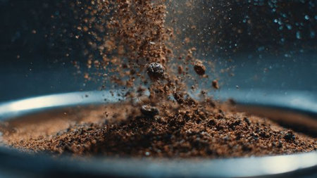 Close-up of ground coffee falling into a glass bowl. Dark background.の写真素材